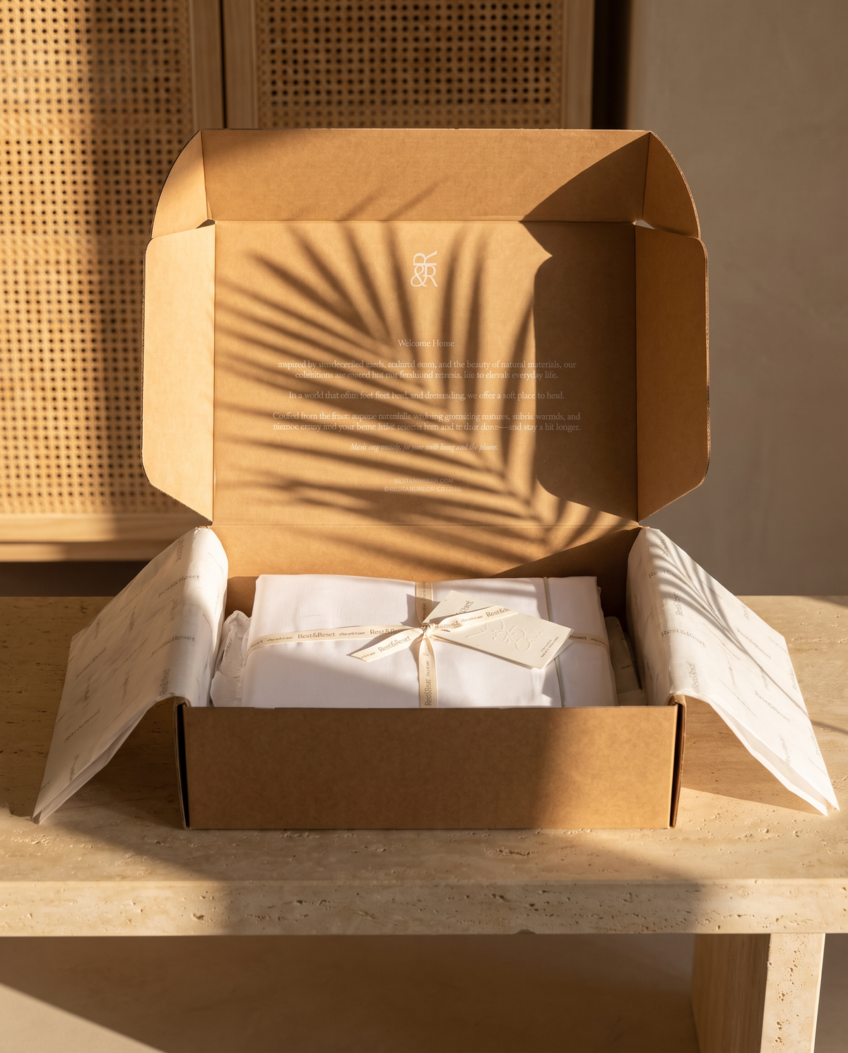Rest & Reset box opened on a limestone bench in golden light, sheets tied with ribbon inside